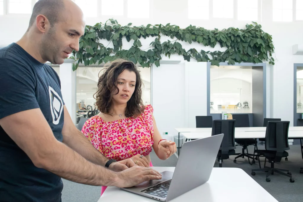 Two professionals working together on a laptop to analyze and verify content.