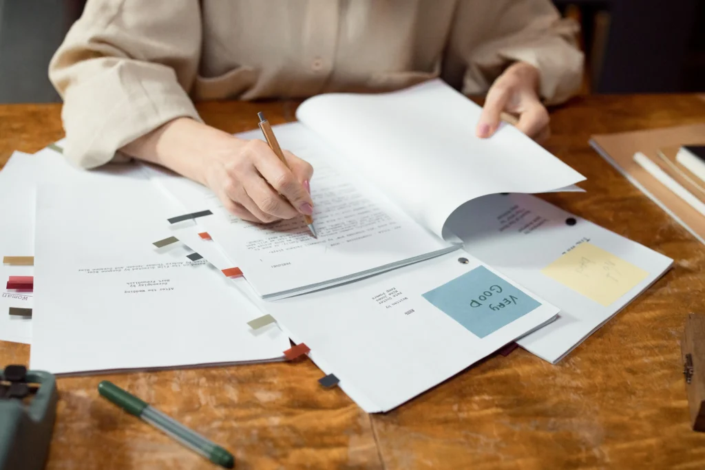 Éditeur relisant et corrigeant des documents imprimés pour vérifier la qualité et l’intégrité des contenus.